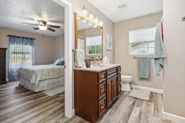 bathroom with plenty of natural light, a ceiling fan, baseboards, and wood finished floors