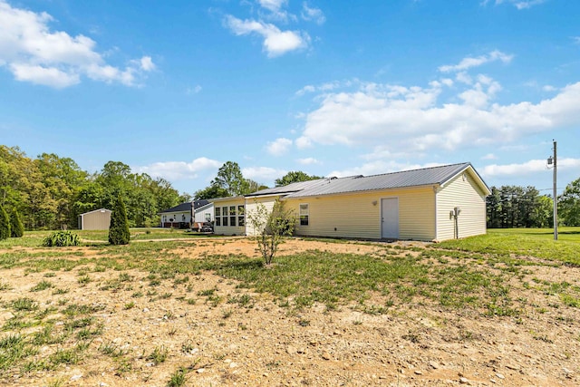back of house with an outdoor structure and metal roof