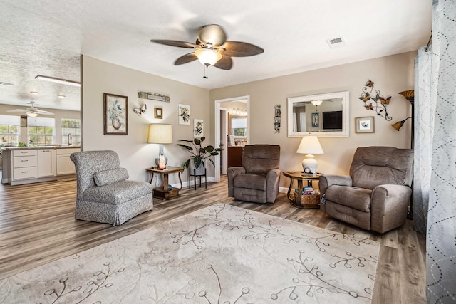 living area with a ceiling fan, baseboards, and light wood finished floors