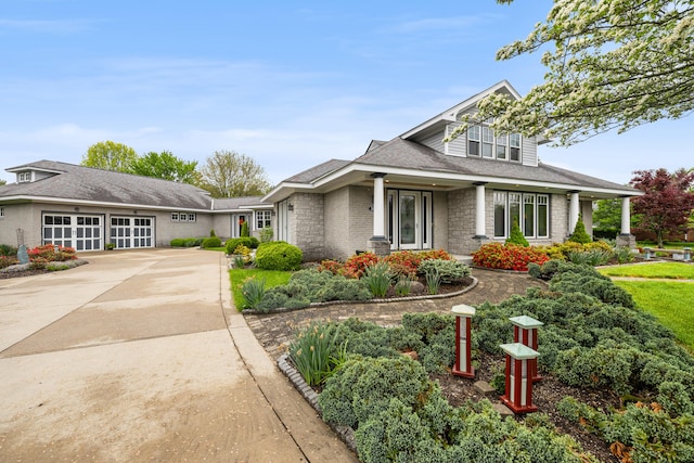 view of front of property with stone siding, driveway, and a garage
