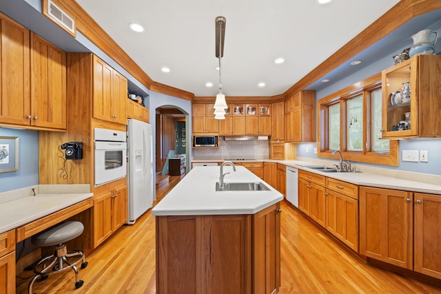 kitchen featuring arched walkways, white appliances, visible vents, and a sink