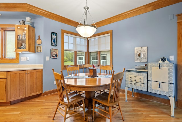 dining room featuring light wood finished floors, crown molding, and baseboards