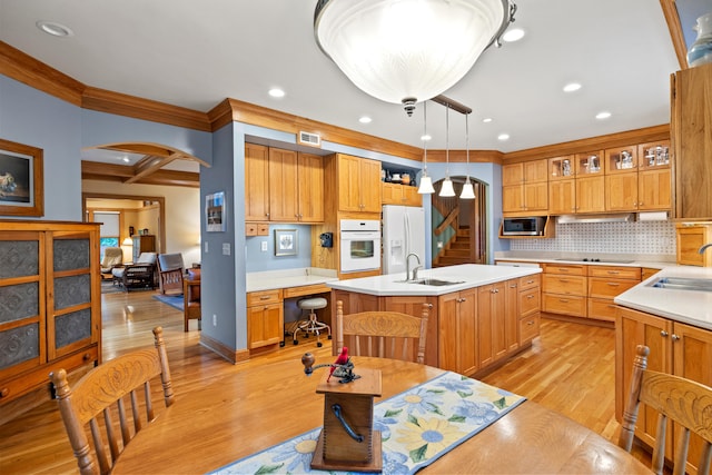 kitchen with a sink, ornamental molding, white appliances, and arched walkways