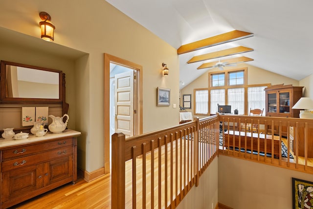 corridor featuring an upstairs landing, baseboards, light wood-style flooring, and lofted ceiling