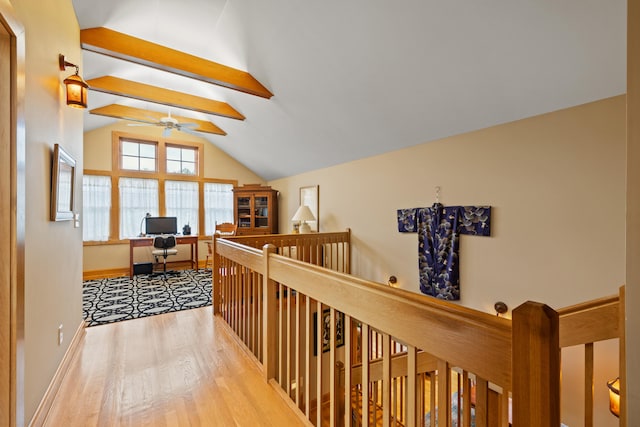 hallway featuring baseboards, lofted ceiling with beams, an upstairs landing, and wood finished floors