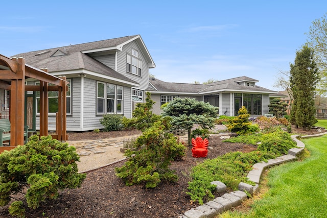 view of side of property with a shingled roof and a yard
