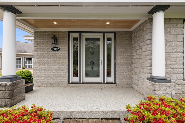 entrance to property with covered porch and brick siding