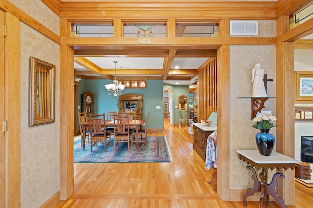 dining room with coffered ceiling, a notable chandelier, visible vents, and wood finished floors