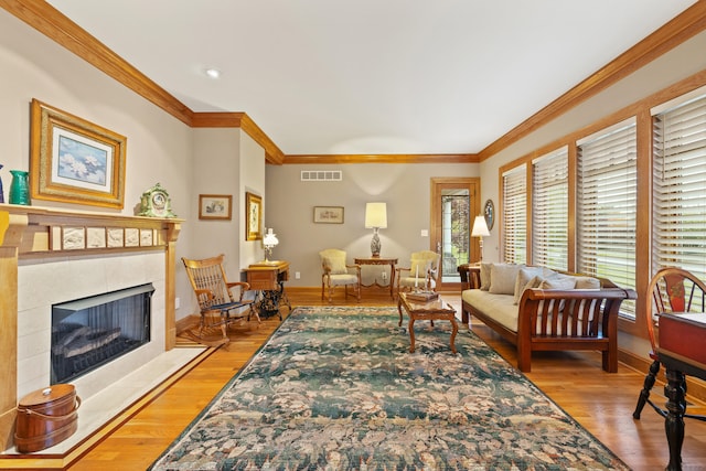 living room with ornamental molding, light wood-type flooring, and visible vents