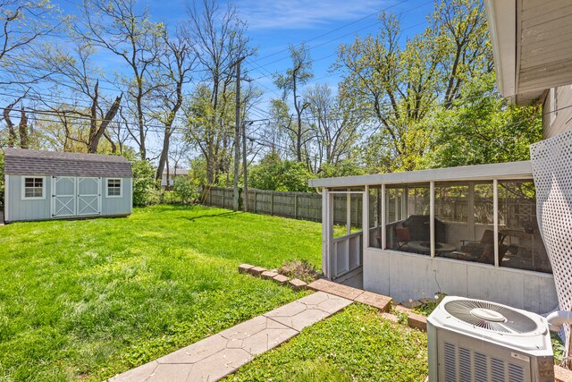 view of yard with a sunroom, central AC unit, an outbuilding, a storage shed, and fence