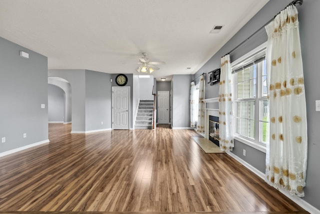 533 Lanarkshire Pl, Lexington, KY 40509 - unfurnished living room with ceiling fan, arched walkways, wood finished floors, stairs, and a glass covered fireplace