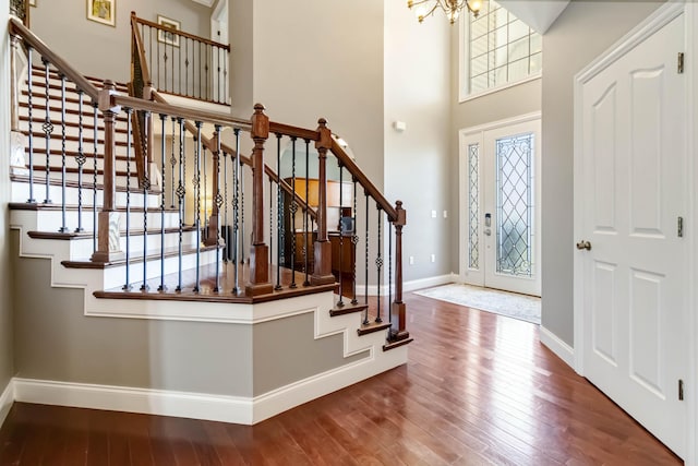 foyer with stairway, hardwood / wood-style floors, baseboards, and a notable chandelier