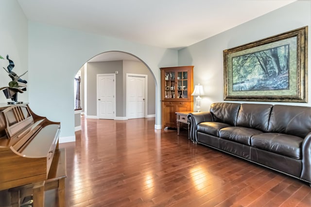 living room featuring hardwood / wood-style flooring, arched walkways, and baseboards