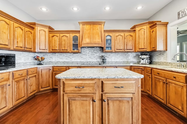 kitchen featuring dark wood finished floors, stainless steel microwave, a sink, and glass insert cabinets