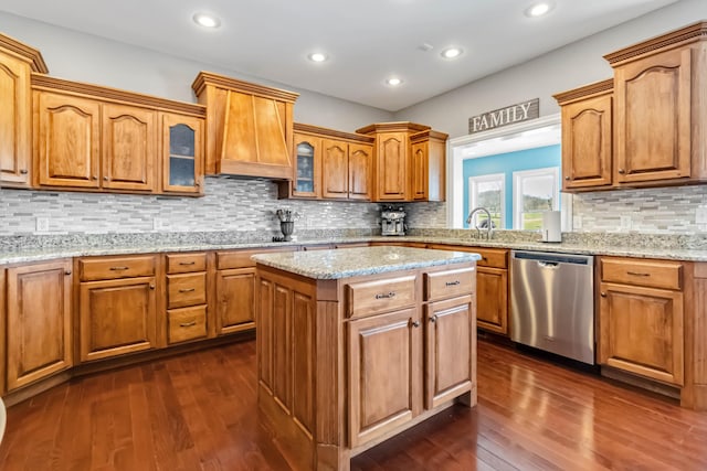 kitchen with dark wood-style flooring, glass insert cabinets, decorative backsplash, dishwasher, and a kitchen island
