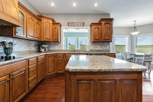 kitchen featuring a center island, tasteful backsplash, dark wood-style flooring, recessed lighting, and brown cabinets