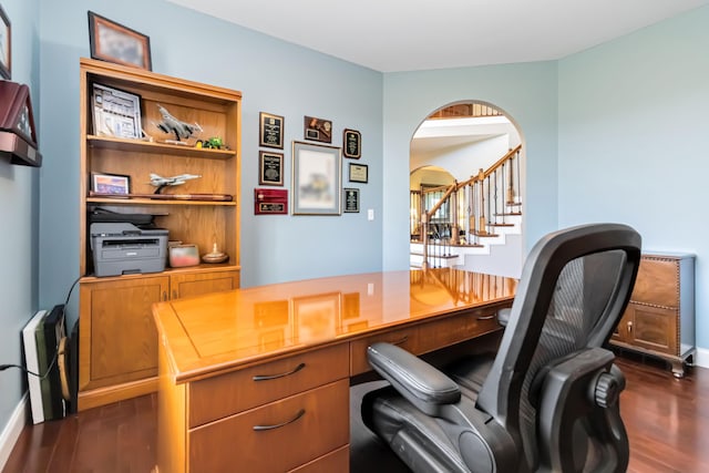 office area featuring arched walkways, dark wood-style flooring, and baseboards