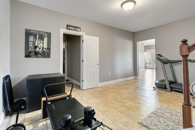 workout room featuring baseboards and light tile patterned floors
