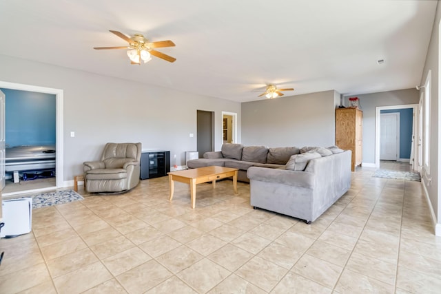 living area featuring baseboards, a ceiling fan, and light tile patterned floors