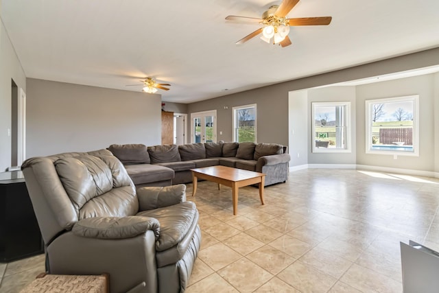 living room featuring baseboards, a ceiling fan, and light tile patterned floors