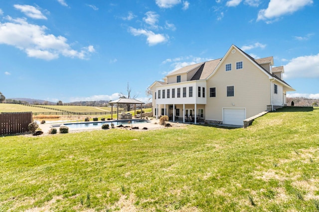 back of property featuring a gazebo, a yard, a garage, and fence