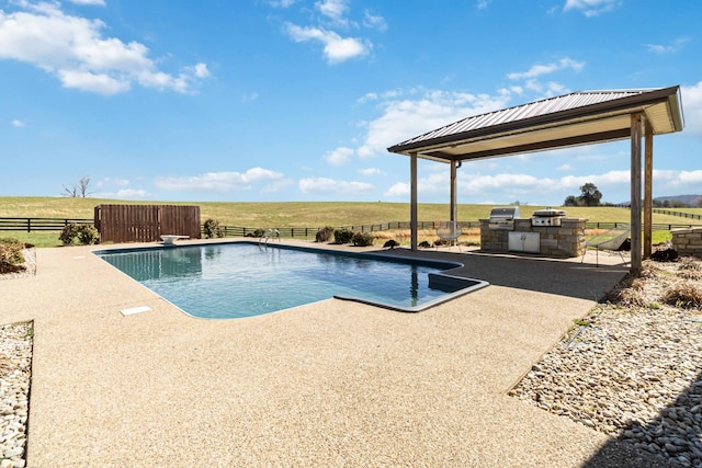 view of swimming pool featuring a fenced in pool, fence, a rural view, area for grilling, and a patio