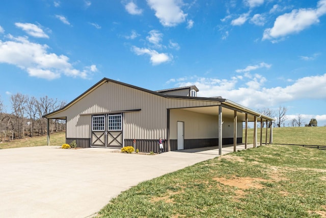 view of side of property with a carport, a lawn, an outdoor structure, and concrete driveway