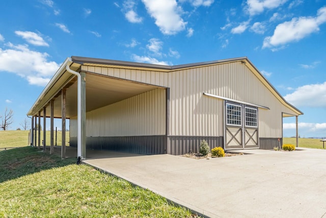 view of property exterior with a carport, driveway, a yard, and an outbuilding