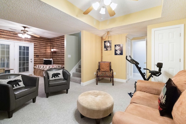 living room featuring stairs, rustic walls, ceiling fan, french doors, and baseboards