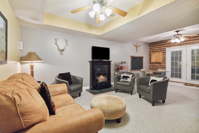 carpeted living room with ceiling fan, rustic walls, a textured ceiling, and visible vents
