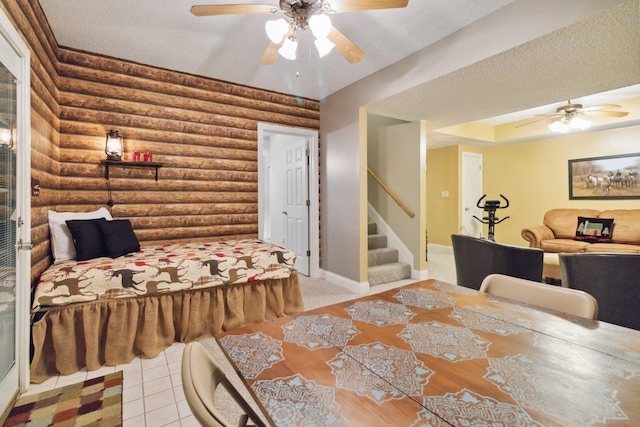 tiled bedroom featuring rustic walls, a ceiling fan, and baseboards