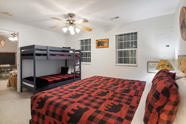 bedroom with electric panel, visible vents, carpet flooring, and a ceiling fan