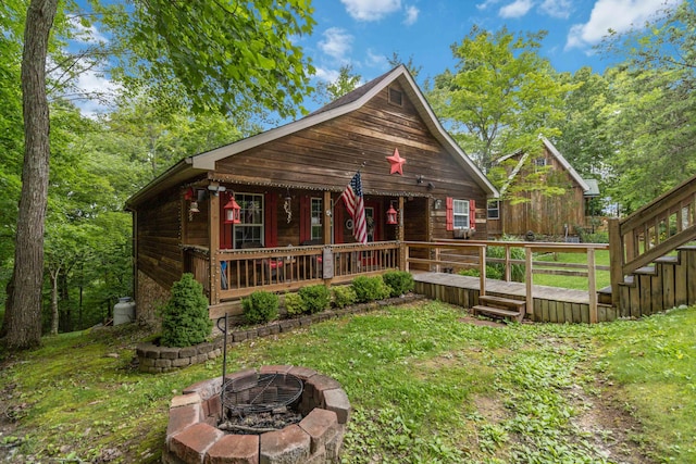 exterior space featuring a porch, a lawn, and an outdoor fire pit