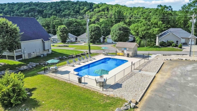 pool with a forest view, a lawn, and fence