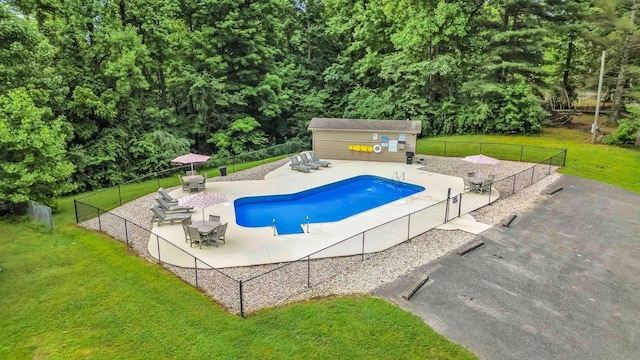 view of swimming pool with a patio area, a lawn, an outdoor structure, fence, and a fenced in pool