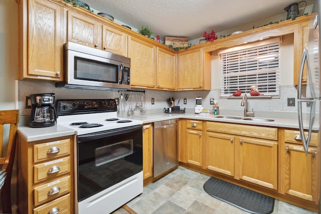 kitchen featuring stainless steel appliances, a sink, a textured ceiling, tasteful backsplash, and light countertops