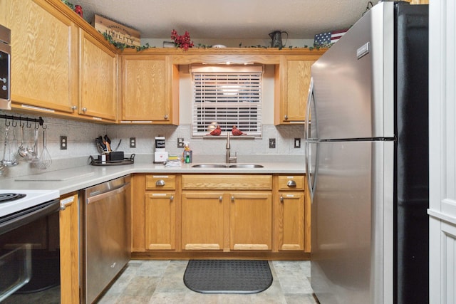 kitchen featuring decorative backsplash, light countertops, a sink, and appliances with stainless steel finishes