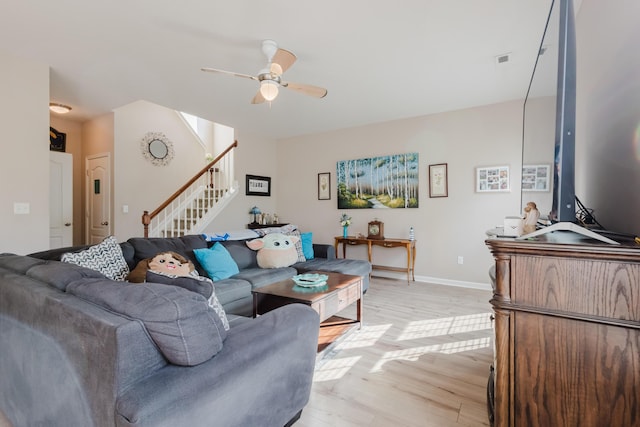 living area featuring visible vents, stairs, light wood-style floors, baseboards, and a ceiling fan