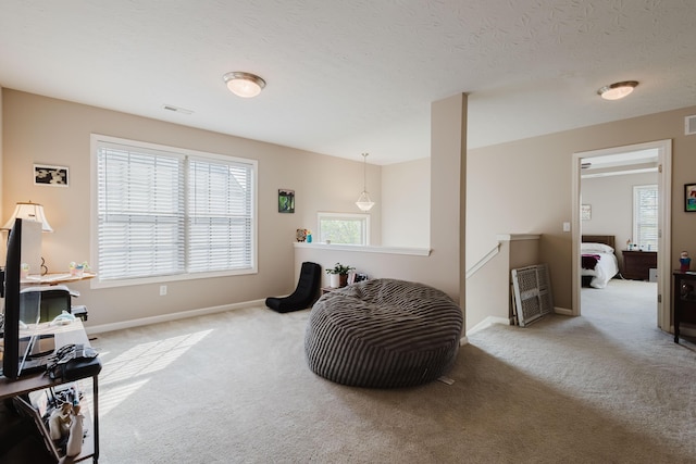 living area featuring carpet floors, baseboards, visible vents, and an upstairs landing