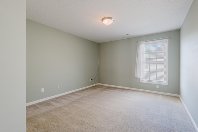 unfurnished room with light colored carpet and baseboards