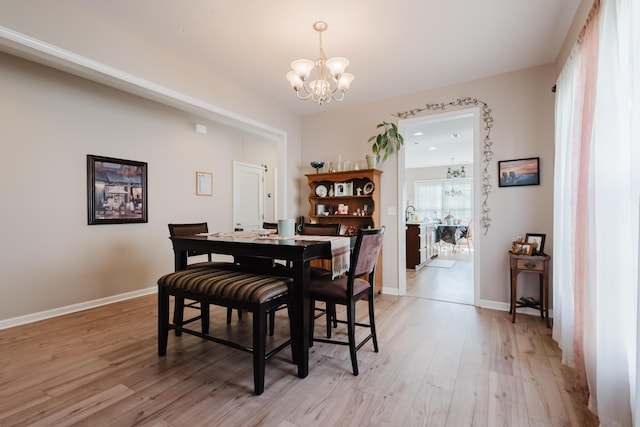 dining space featuring baseboards, a chandelier, and light wood-style floors