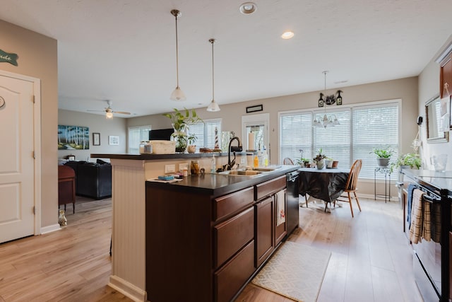 kitchen with dark countertops, a sink, light wood finished floors, dishwasher, and range with electric stovetop
