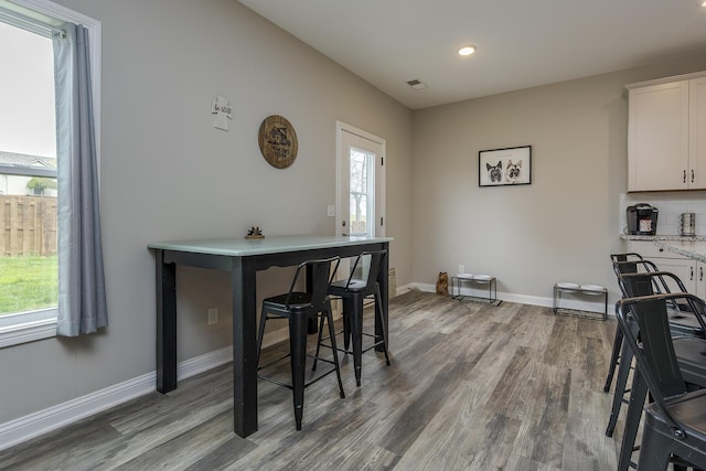 dining space with baseboards, wood finished floors, visible vents, and recessed lighting