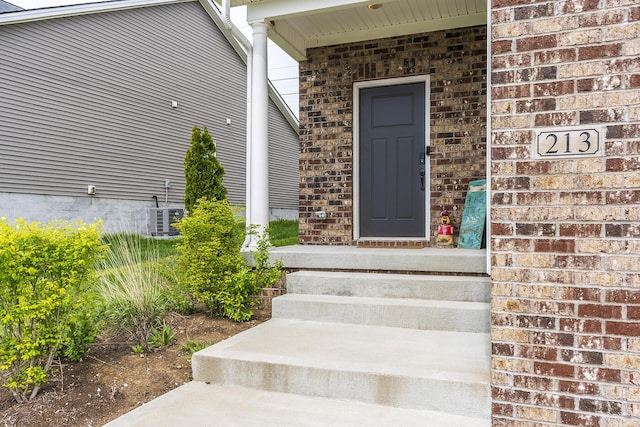 doorway to property with brick siding and cooling unit