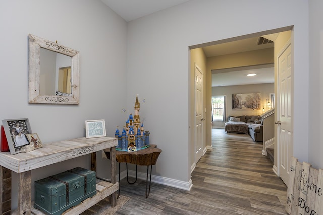 corridor featuring visible vents, baseboards, and wood finished floors