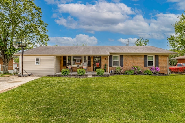 ranch-style home featuring covered porch, brick siding, fence, and a front yard