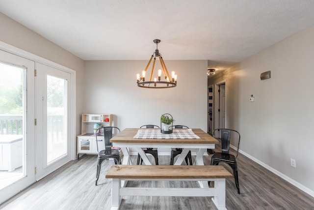dining space with baseboards, an inviting chandelier, and light wood finished floors