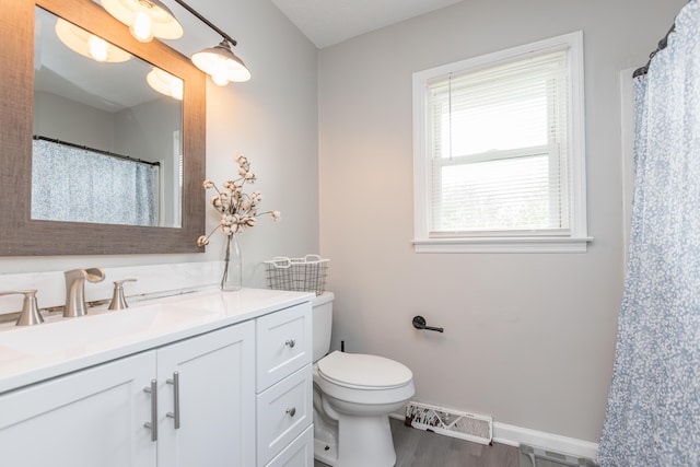 full bath featuring visible vents, wood finished floors, vanity, baseboards, and toilet