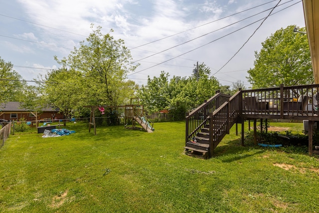 view of yard with a wooden deck, a fenced backyard, and stairs