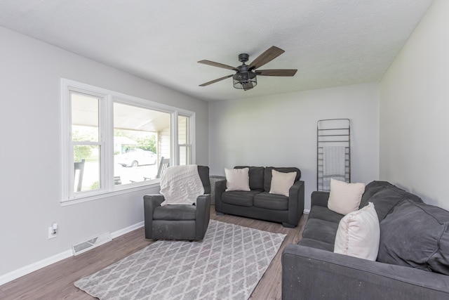 living room featuring baseboards, a ceiling fan, wood finished floors, and visible vents